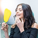 woman admiring her reflection after getting dental implants in Loveland 