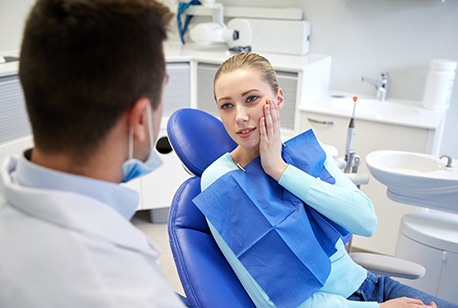 Woman holding cheek during emergency dental appointment