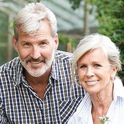 Older man and woman smiling in their front yard