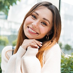 Woman in white sweater smiling outdoors