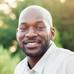 Man in white polo shirt smiling outdoors