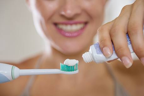 Woman putting toothpaste on toothbrush