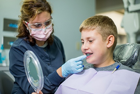 Young boy looking at teeth in mirror during dental checkup