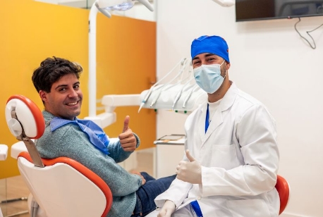 Happy dentist and patient making thumbs-up gesture