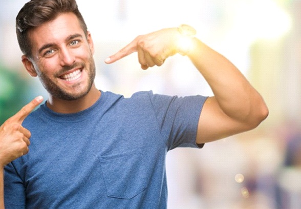 man pointing to his smile after getting cosmetic dental bonding in Loveland