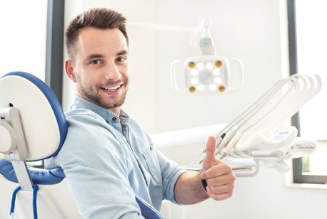 smiling man giving thumbs up in dentist’s chair