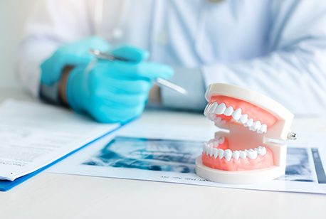 Dentures model next to X-ray, paperwork, and dentist