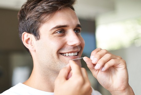 Man flossing teeth to prevent dental emergencies