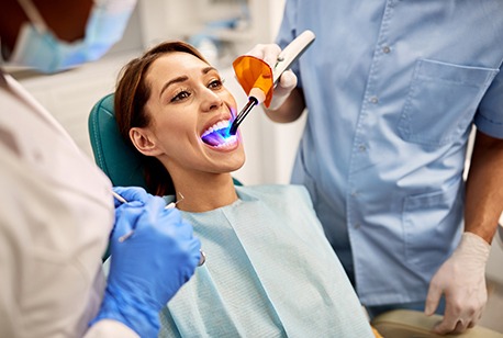 Woman having a UV light shined on her tooth