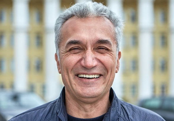 Older man with implant dentures in Loveland smiling outside