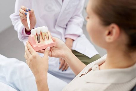 dentist showing a dental implant model to a patient