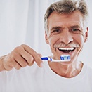 man in a white T-shirt brushing his teeth