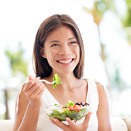 a woman eating a salad for dental implant care