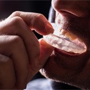 a man putting on a mouthguard for dental implant care