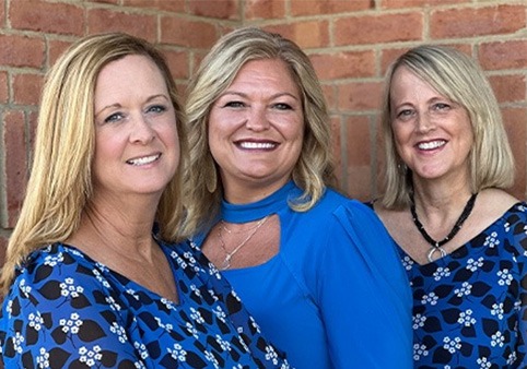 Three Loveland dental team members smiling in blue shirts