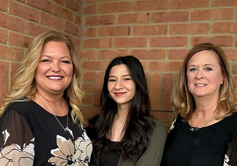 Three Loveland dental team members smiling in blue shirts