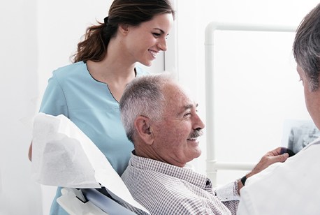 Older man in dental office discussing full-mouth reconstruction options