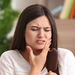 Woman in need of emergency dentistry holding jaw