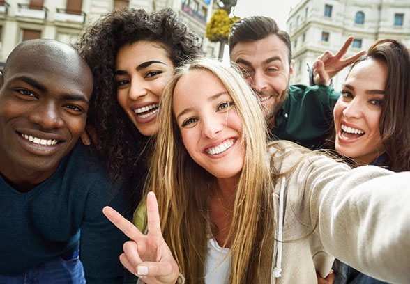 A group of young people smiling and enjoying each other’s company after seeing a dentist near Cincinnati