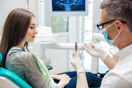 A dentist explaining how dental implants work to a female patient