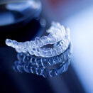 Two stacked clear aligners sitting on reflective surface