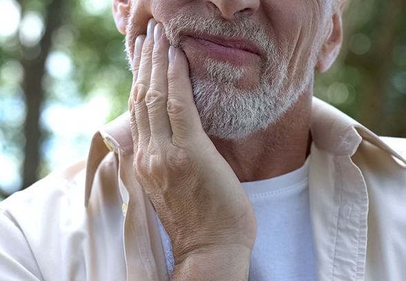 Bearded man rubbing jaw, in need of TMJ treatment in Loveland, OH
