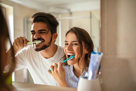 Man and woman brushing teeth to preserve teeth whitening results