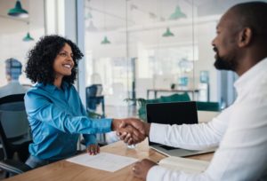 Woman and man smiling and shaking hands in an office