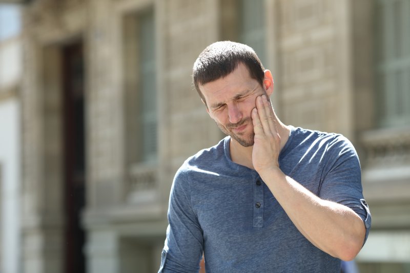 Man outside suffering from TMJ pain