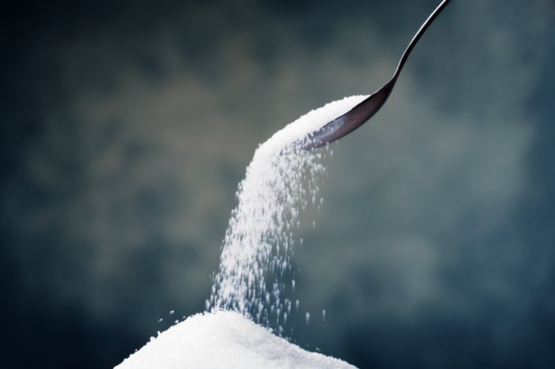 A spoon scooping up a pile of sugar